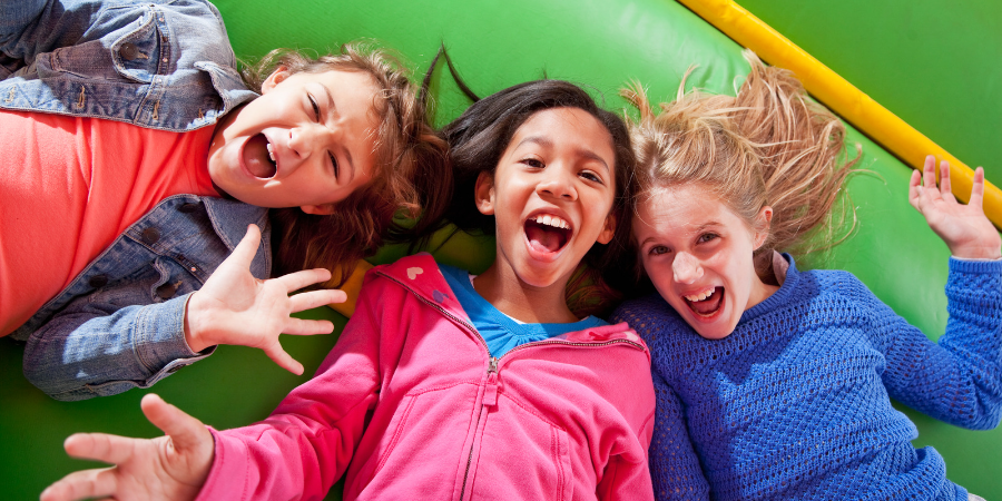 Image of kids in a bounce house laying on their backs with smiles on their face.