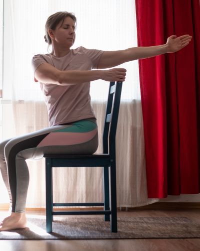 Woman practicing chair yoga.