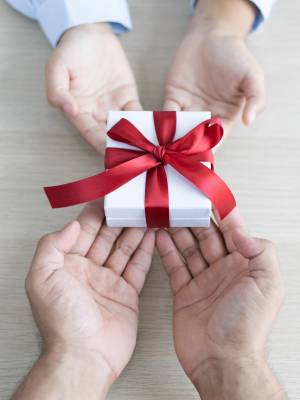 a person giving a gift to another person; only showing hands