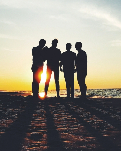 Group of men on a beach backlit by the sun.
