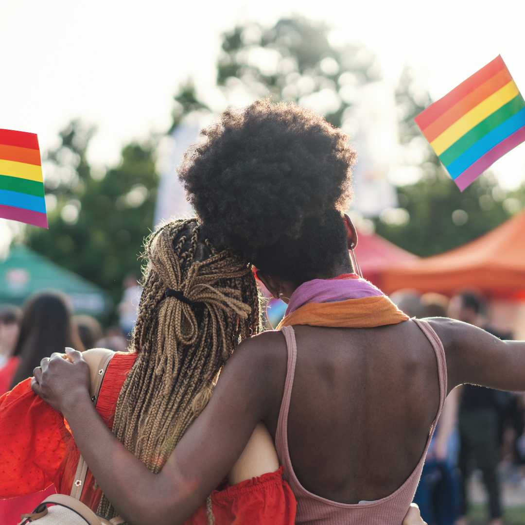 Image of two women holding up pride flags.