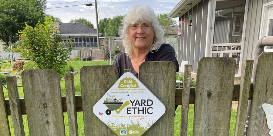 Image of Ann behind a fence with her certification plaque.