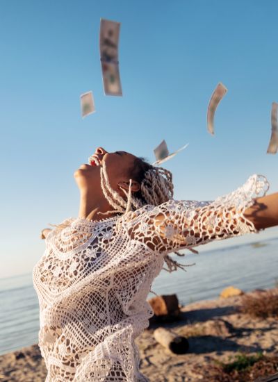 Person with arms outstretched with money raining down from the sky.