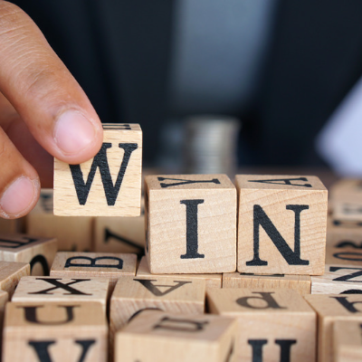 Image of someone spelling out "win" using blocks with letters on them.