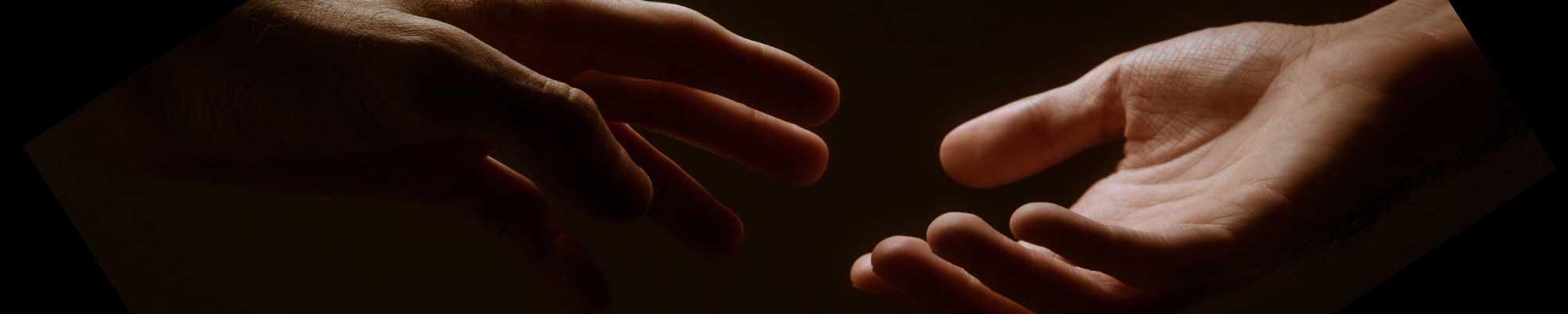 An image of a hand reaching to another hand.