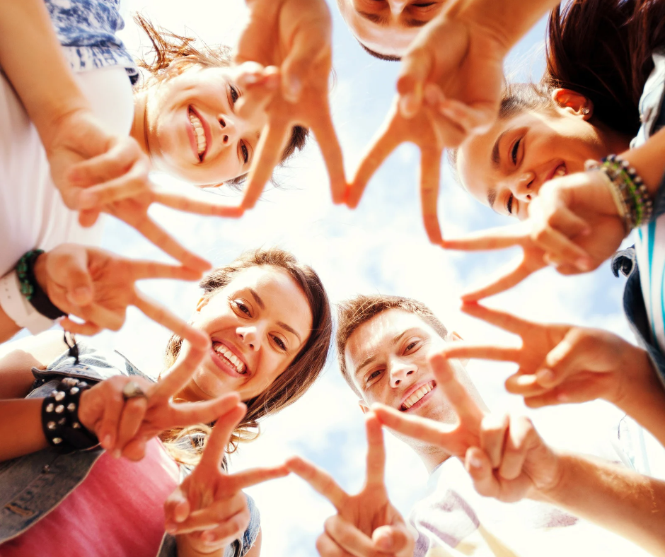 Image of a group of teenagers standing in a circle holding up peace signs.